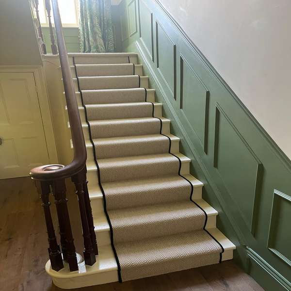 A wooden staircase with a blue and beige striped carpet runner.